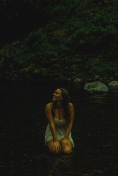 a woman is sitting in the water with her hands on her knees and eyes closed