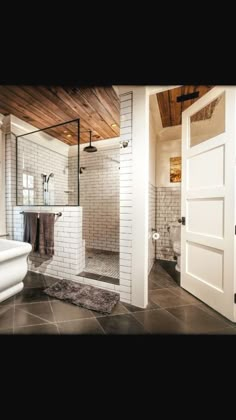 a bathroom with white brick walls and black tile flooring, along with a walk in shower