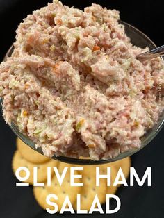 a close up of a bowl of food with crackers in the background and text overlay that reads olive ham salad