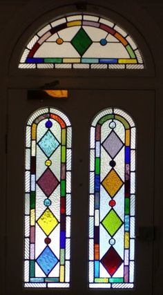 two stained glass windows in the middle of a door with an arched window above them