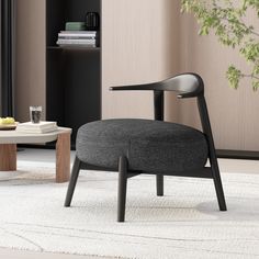 a black chair sitting on top of a rug next to a table and bookshelf