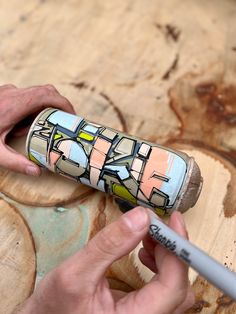 a person is using a marker to draw on a piece of wood that has been painted