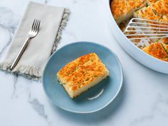 a piece of quiche on a blue plate next to a white dish with a fork