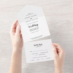 two hands holding up some white wedding cards