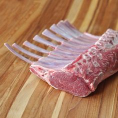 a piece of raw meat sitting on top of a wooden table next to a fork