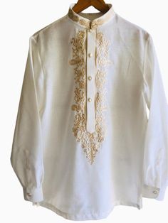 a white shirt with gold embroidery on the collar