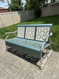 a blue and white bench sitting on top of a brick patio next to a fence