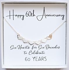 a white box with a silver heart necklace in it's gift box, and the words happy 60th anniversary written on it