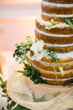 a wedding cake with flowers and greenery on top