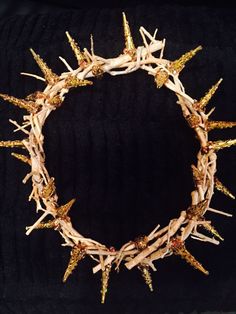 a crown made out of branches with gold spikes on it's sides and two rows of nails sticking out of the middle