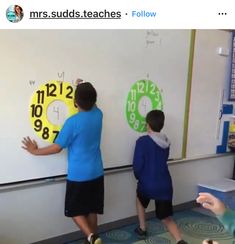 two boys are writing on a whiteboard with numbers and times in front of them