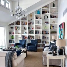 a living room filled with lots of furniture and bookshelves covered in white bookcases