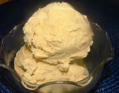 two scoops of ice cream sit in a glass bowl on a blue tablecloth