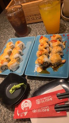 two blue plates topped with sushi next to a drink