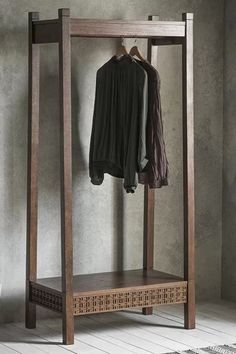 an open wooden coat rack with clothes hanging on the hangers in front of it