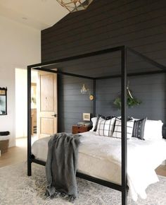 a bedroom with a four poster bed and black walls