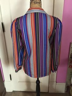 "Vintage 1970's striped blouse. Is a silky feel Polyester. No makers label/tag. *MORE INFORMATION BELOW* CONDITION: I note a few bumps on the top layer of the fabric on the collars (SEE PIX). MEASURES: Bust~38\" Waist~36\" Hips~42\" Sleeve length~23\" Shoulder seam to shoulder seam~14\" Back of collar to bottom~25 1/2\" *WE APOLOGIZE~BUT WE NO LONGER SHIP TO GERMANY, ITALY OR SPAIN. IF ORDERS COME IN FROM GERMANY, ITALY OR SPAIN, WE WILL HAVE TO CANCEL THEM AND REFUND YOUR MONEY. SORRY FOR THIS Multicolor Long Sleeve Top With Vertical Stripes, Retro Long Sleeve Top With Striped Collar, Retro Fitted Striped Blouse, Retro Striped Fitted Blouse, Retro Striped Long Sleeve Blouse, Retro Striped Collared Blouse, Vintage Long Sleeve Tops With Vertical Stripes, Vintage Striped Collared Tops, Retro Long Sleeve Striped Blouse