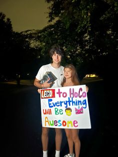 two people standing next to each other holding a sign that says i love you to hola everything will be awesome