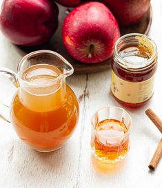 apple cider, cinnamon sticks and apples on a table