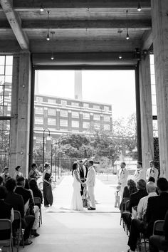 a bride and groom are getting married at the end of their wedding ceremony in front of an industrial building