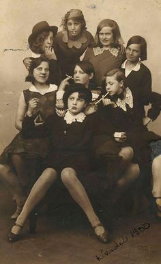 a group of women sitting next to each other in front of a wooden sign with spanish writing