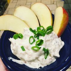 a blue bowl filled with white sauce and sliced apples on top of a counter next to a tile floor