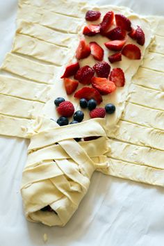 an unwrapped pastry with strawberries and blueberries on it