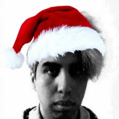 a young man wearing a santa hat and looking at the camera with an intense look on his face