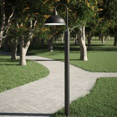 a lamp post sitting in the middle of a walkway next to some grass and trees