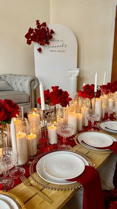 the table is set with candles, plates and red napkins on top of it