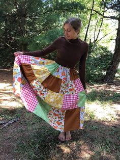 a woman is standing in the woods holding a colorful skirt