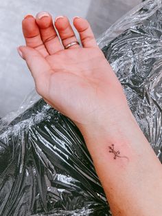 a person's hand with a small tattoo on it, resting against a plastic bag