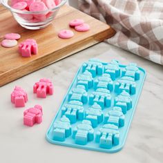 pink and blue ice cubes are on a counter next to a bowl of candy