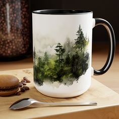 a coffee mug sitting on top of a wooden table next to a spoon and cup