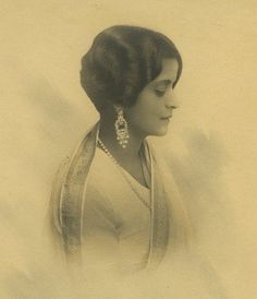 an old photo of a woman in a white dress with pearls on her necklace and earrings