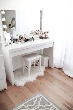 a white desk with two stools in front of it and a mirror on the wall