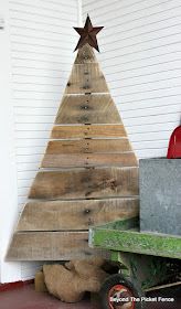 a wooden christmas tree sitting on top of a green cart next to a white wall