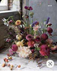 a bouquet of flowers sitting on top of a wooden table next to a window sill