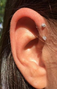 a woman's ear with three small diamond studs on the middle of it