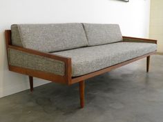 a couch sitting on top of a wooden frame in front of a white brick wall