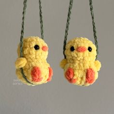 two small yellow stuffed animals hanging from strings