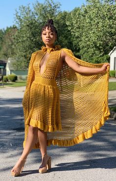 a woman wearing a yellow crochet dress and sandals is walking down the street