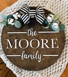 a wooden sign that says the moore family on it with cotton flowers and eucalyptus leaves