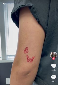 a woman's arm with two red butterflies on the left side of her arm