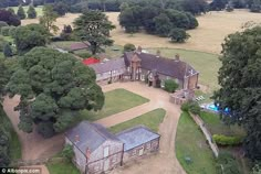 an aerial view of a large house in the middle of a field with lots of trees