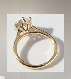 a yellow gold ring with a leaf design on the side and a diamond in the middle