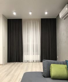 an empty living room with black curtains and white drapes