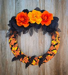 an orange and black wreath decorated with flowers