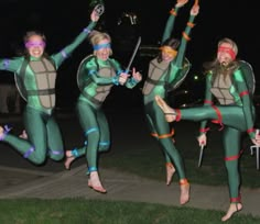 four women in bodysuits are jumping and posing for the camera