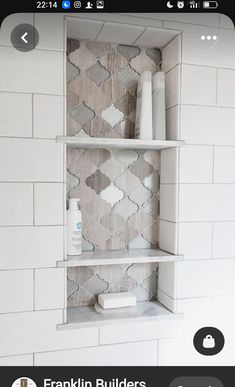 a white shelf with some candles and other items on it in front of a tiled wall